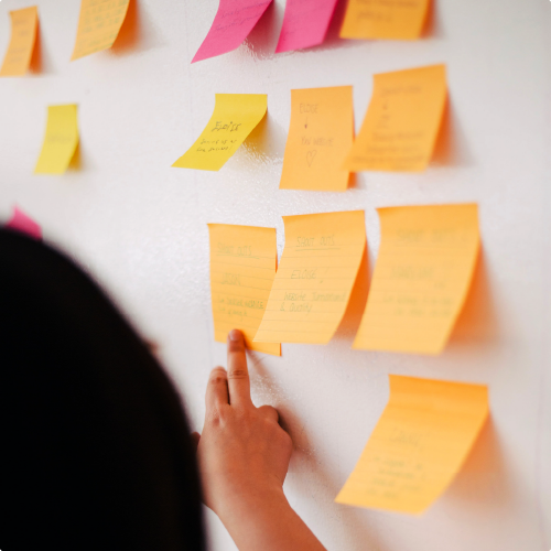 Señorita leyendo una nota post-it pegada en un pizarrón blanco.